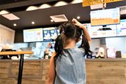 Petite fille devant le menu d’un fast-food