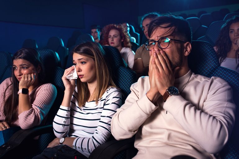 Des spectateurs pleurent en regardant un film au cinéma