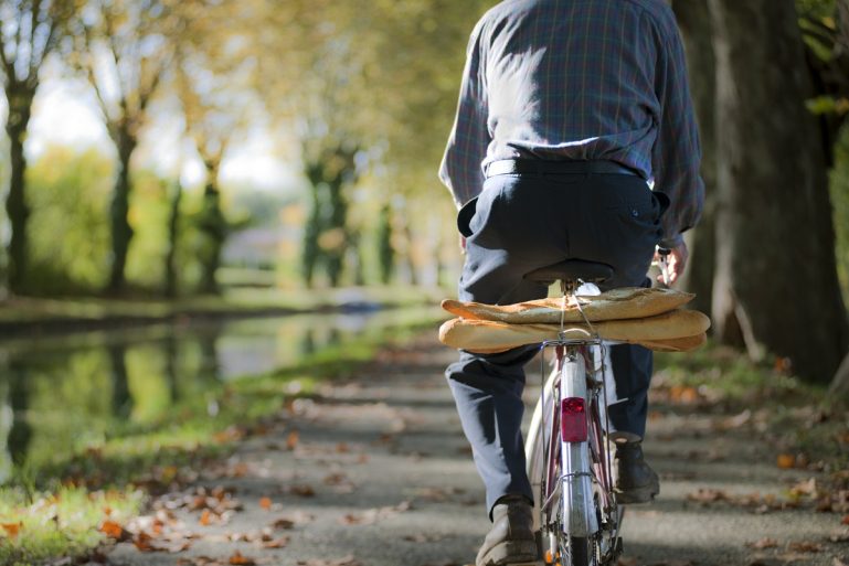 Un homme à vélo avec des baguettes de pain sur le porte-bagages