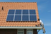 Un artisan termine l'installation de panneaux solaires sur un toit.