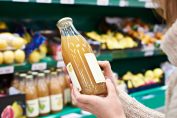 une consommatrice lit l’étiquette d’un jus de pomme
