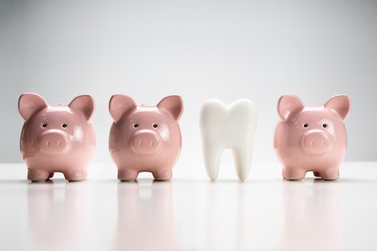 Des tirelires cochons encadrent une dent.