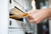 Une femme glisse une enveloppe dans une boîte aux lettres.