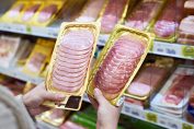 Une consommatrice tient deux packs de rôti de porc entre les mains.