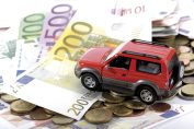 Une voiture en jouet grimpe sur une pile de pièces et de billets