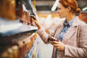 Une consommatrice lit une étiquette de prix en rayon;