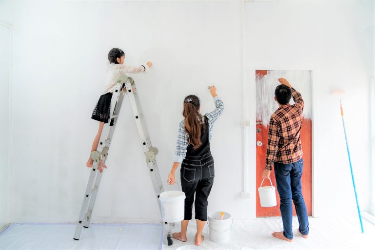 Une famille repeint un mur de son logement.