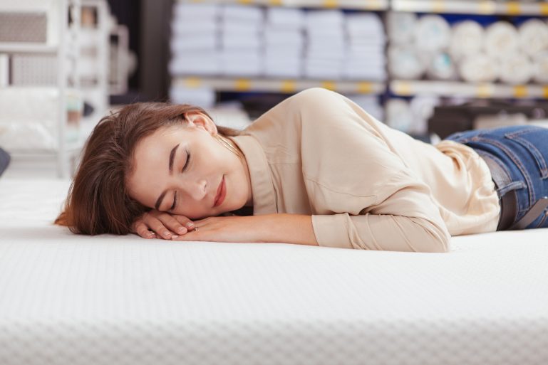 Une femme essaye un matelas dans un magasin.