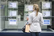 Une femme regarde les annonces en vitrine d'une agence.