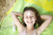 Une petite fille avec des figures dessinées à la crème solaire sur le visage