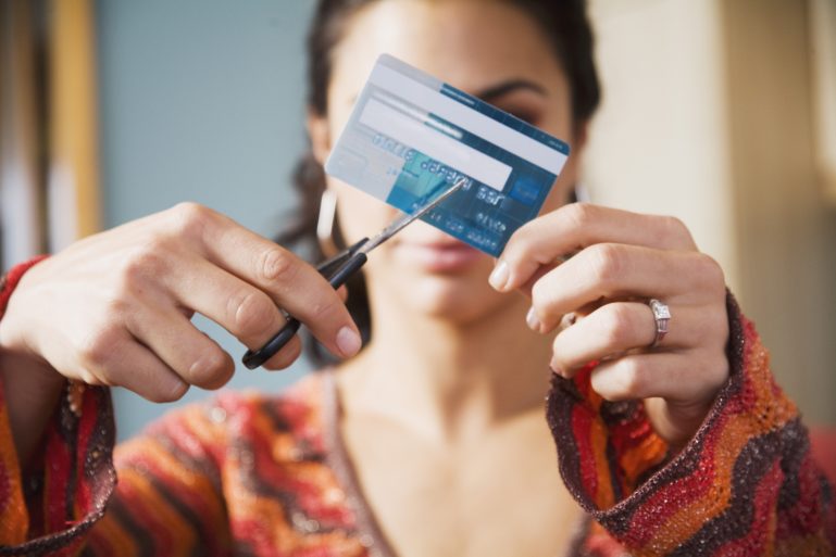 Une femme découpe sa carte bancaire aux ciseaux