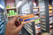 Un pharmacien tient entre ses doigts une boîte de Doliprane