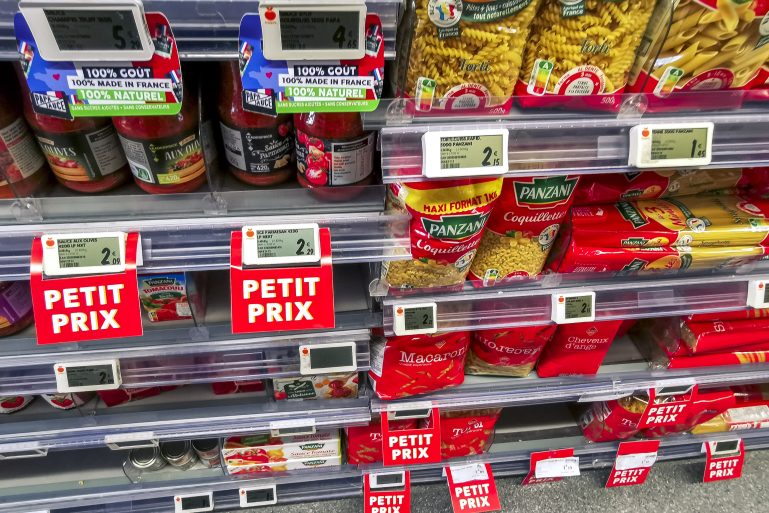Des étiquettes indiquant de petits prix dans les rayons d’un magasin alimentaire.