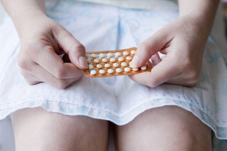 une femme tient une plaquette de pilules contraceptives
