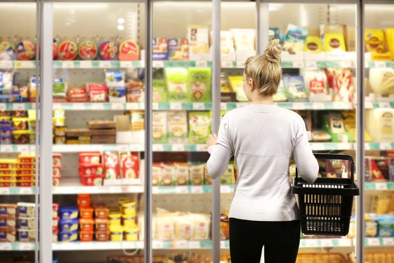 Une femme choisit des produits dans un rayon frais de supermarché
