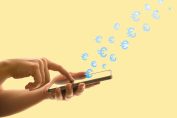 Une main sur un smartphone d'où s'envolent des euros