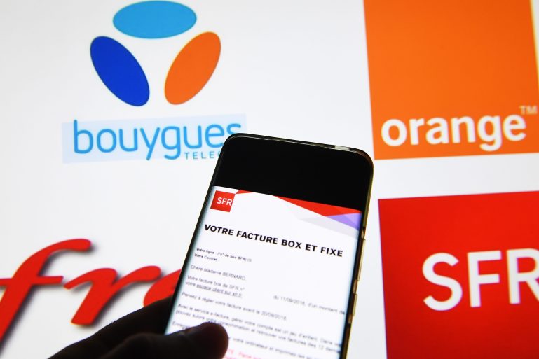 Une facture de box fixe devant les logos des opérateurs