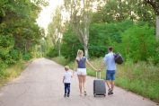 Une famille marche sur une route avec ses bagages