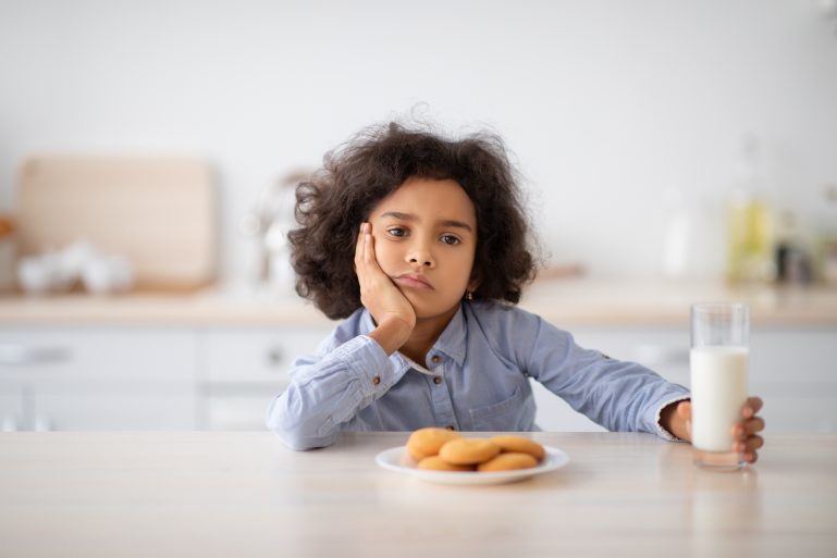 Une petite fille dubitative devant ses biscuits
