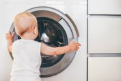 Un bébé devant un lave-linge hublot