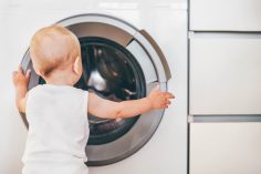 Un bébé devant un lave-linge hublot