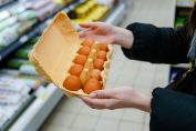 Une femme tient une boîte d’œufs dans un magasin