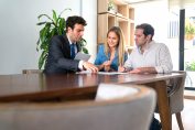 Un démarcheur attablé avec un couple de particuliers