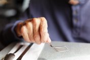 personne très âgée tenant une fourchette
