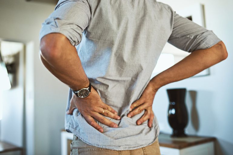Un homme se tient le bas du dos en raison d'une douleur
