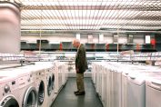homme dans le rayon lave-linge d'un Darty