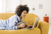 une jeune femme devant son ordinateur, carte bancaire à la main