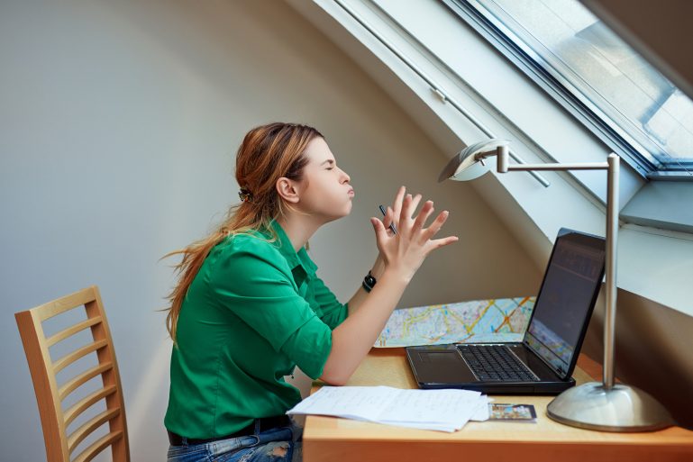 Une femme en colère devant sa carte du monde et son ordinateur.