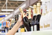 Une acheteuse prend une bouteille de champagne dans un rayon.