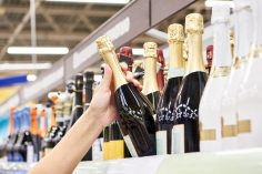 Une acheteuse prend une bouteille de champagne dans un rayon.