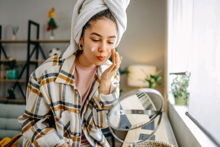 femme s’appliquant de la crème sur le visage