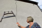 Une femme constate une fissure sur la façade de sa maison.