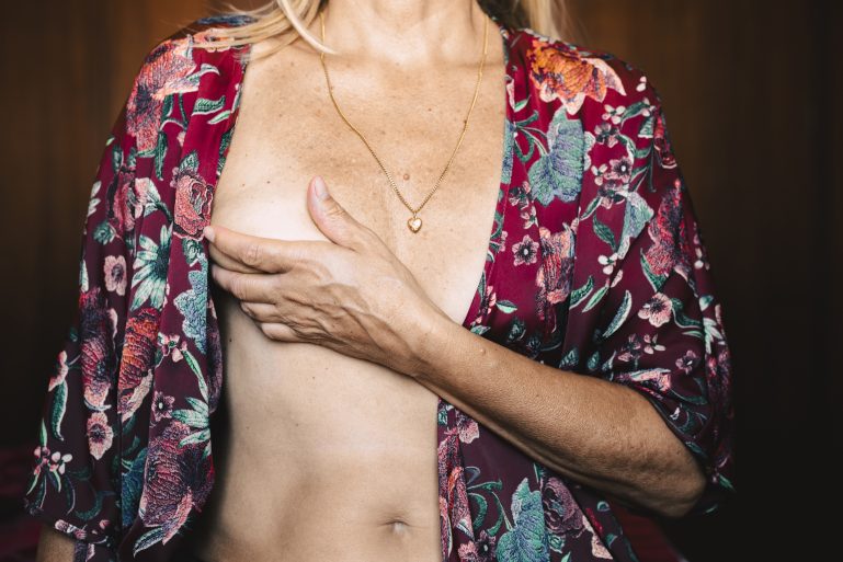 Une femme en peignoir tenant son sein