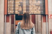 Jeune femme devant un panneau d'affichage des trains