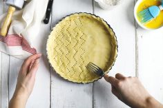 Une pate à tarte dans un moule en train d'être piquée
