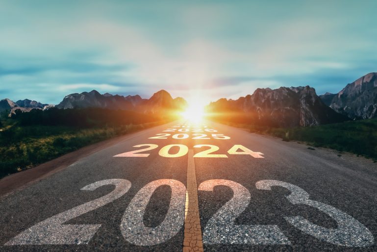 “2023”, “2024” et “2025” écrit sur une route au soleil couchant