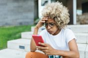 Une femme consternée en consultant son smartphone