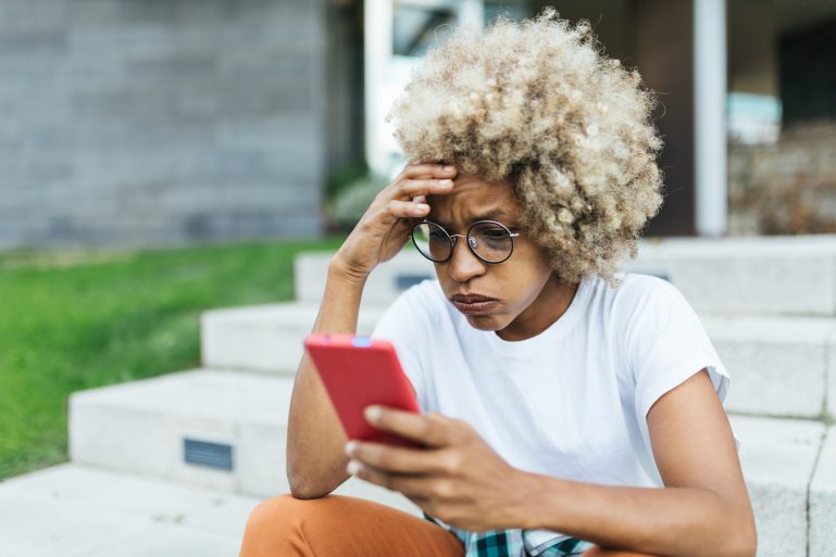 Une femme consternée en consultant son smartphone