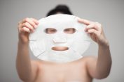 Une femme s'apprête à mettre un masque de beauté à usage unique