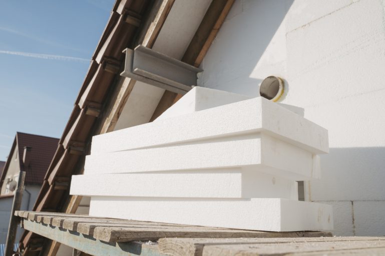 Des matériaux d'isolation devant une maison en chantier