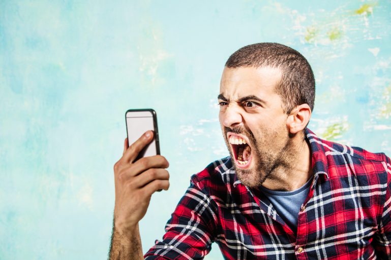 Un homme vert de rage hurle dans son smartphone