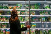 Une consommatrice choisit une salade en sachet dans un rayon