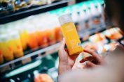 une consommatrice lit l'étiquette d’un jus de fruits