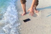 smartphone tombé sur le sable et mouillé par la mer