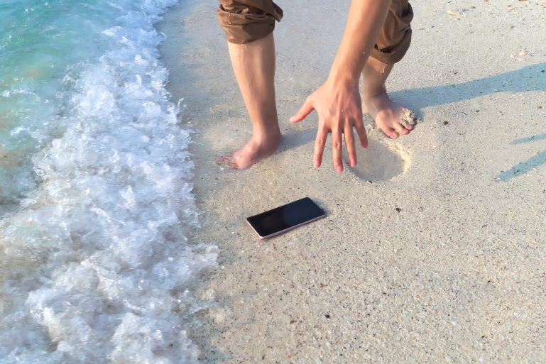 smartphone tombé sur le sable et mouillé par la mer