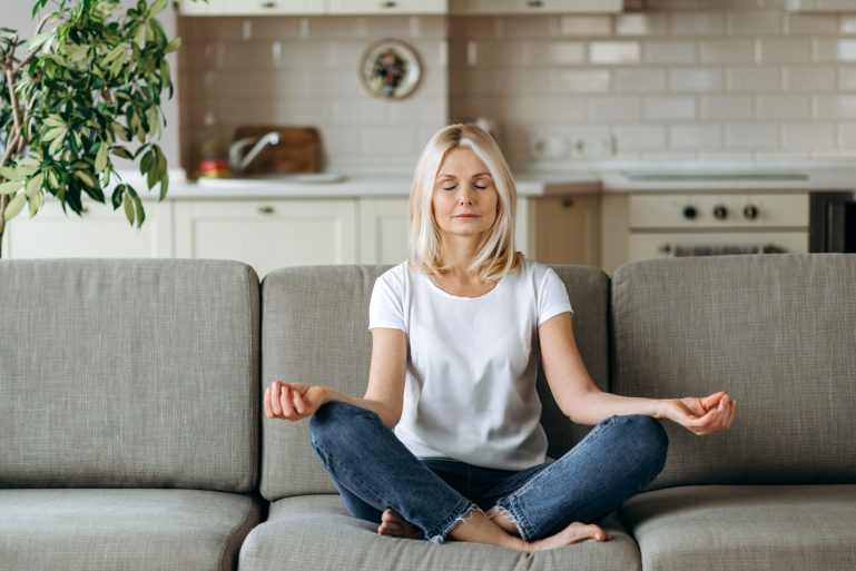 Une femme en position du lotus sur son canapé